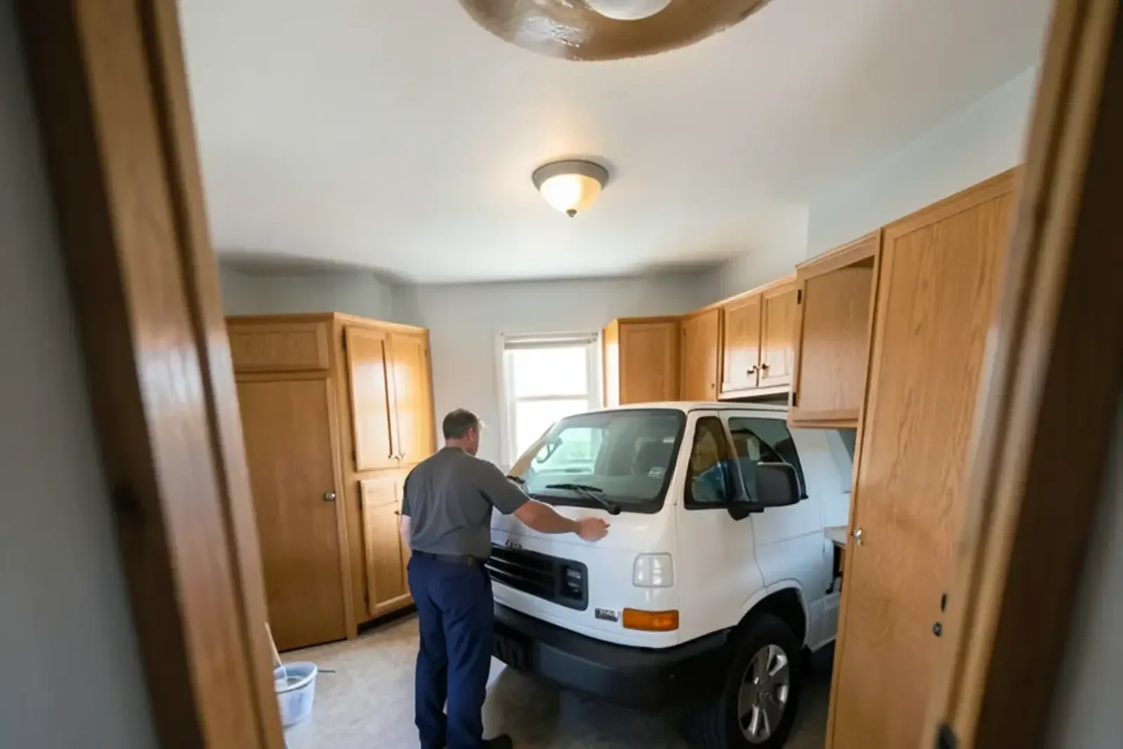 Brown water ring on the drywall ceiling of a condo kitchen beneath an upstairs unit, with a bucket on the floor
